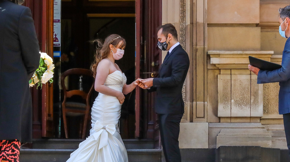 Masked couple getting married in microwedding