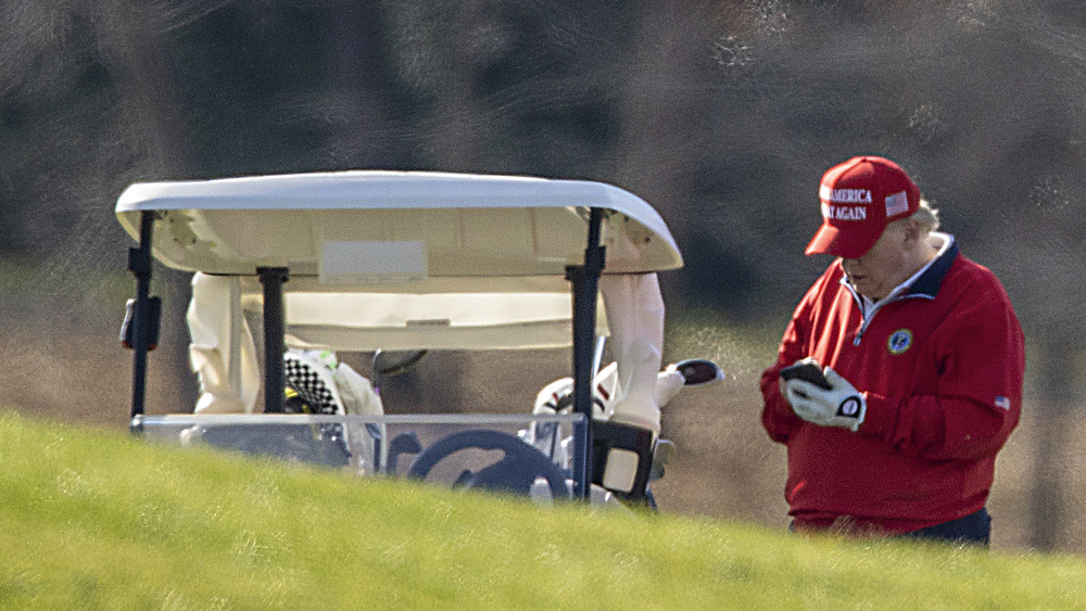 Donald Trump using his phone on the golf course