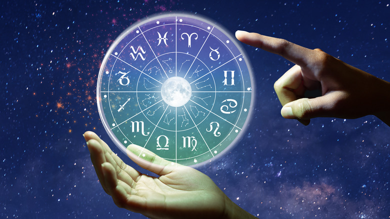 Hand pointing to a zodiac chart