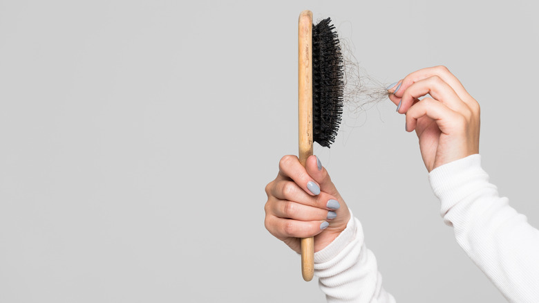 woman pulling an access amount of hair out of a brush 