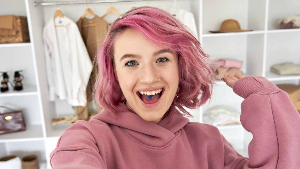 girl with pink hair, wearing pink hoodie, smiling