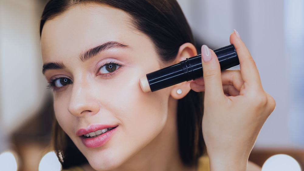 A woman applies stick foundation 