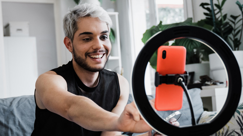 Person using a ring light and phone to record a video