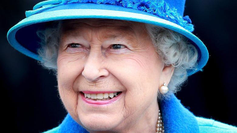 Queen Elizabeth smiling while wearing a blue suit