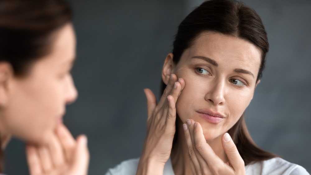 Woman examining dry skin in the mirror