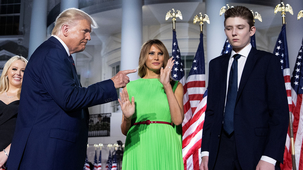 Barron Trump looking unhappy as President Trump points at him with Melania Trump