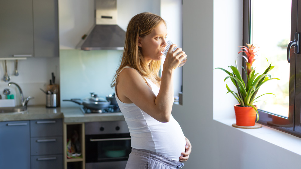 A pregnant woman drinking from a glass 