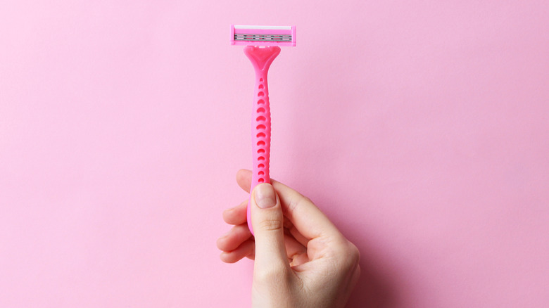 Hand holds pink plastic razor