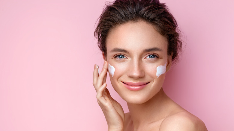 woman applying lotion to face