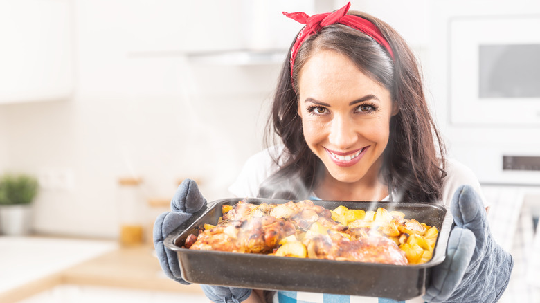 Woman holding a tray of meat and potatoes in her hands