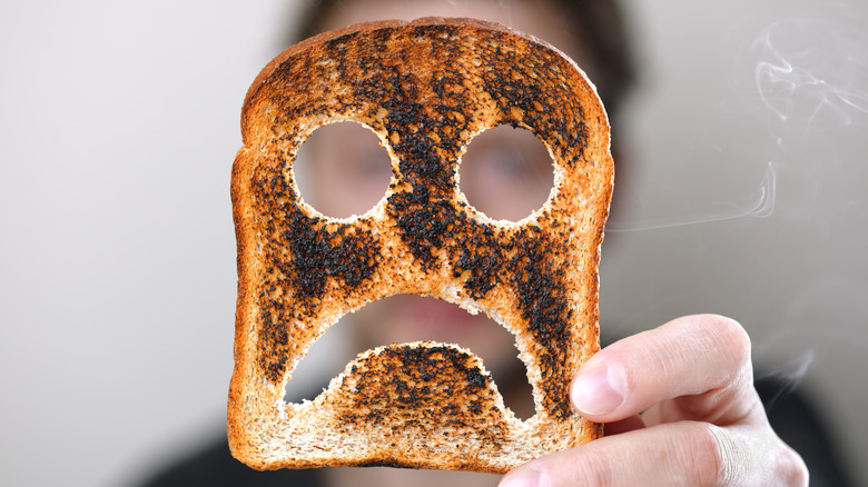 Woman holding a slice of burnt toast