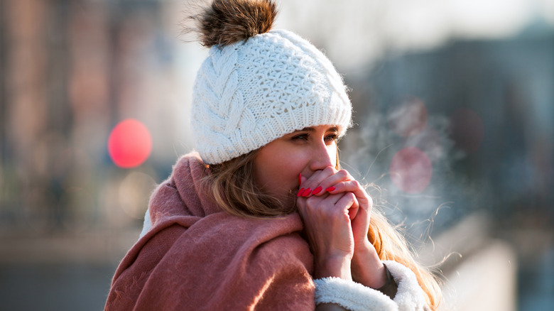 A woman wearing a beanie and scarf outdoors 