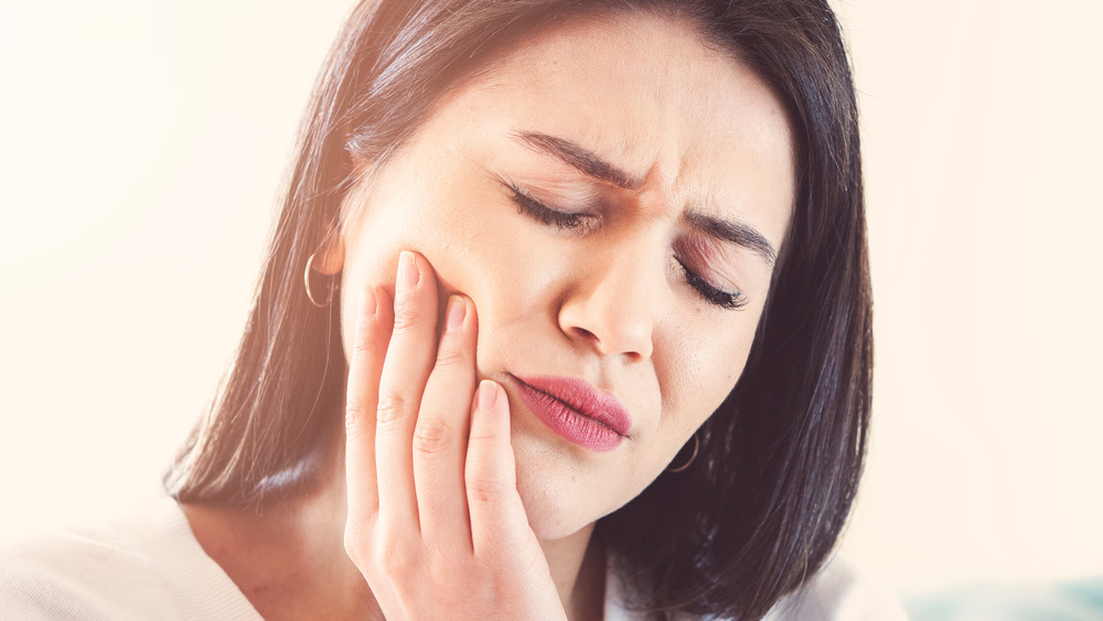 A woman in pain, touching her cheek 