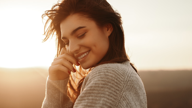 Young woman smiling while wearing a sweater