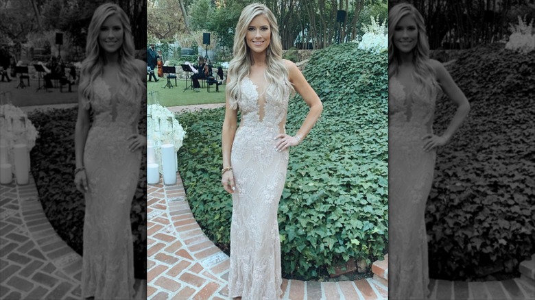 Christina Haack standing alone in champagne gown with ivy behind her.