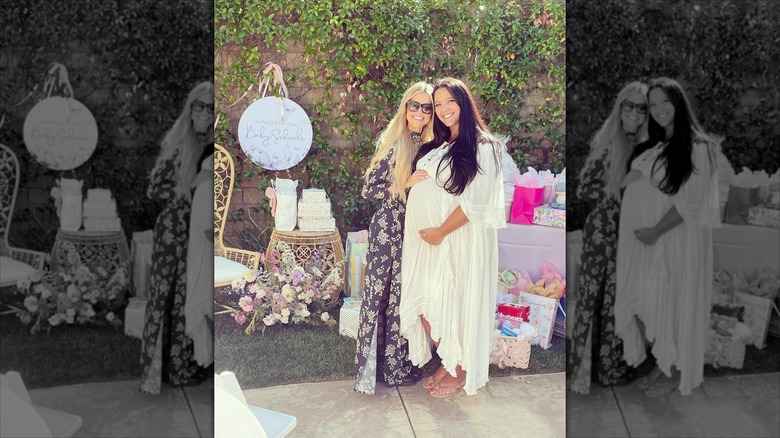 Christina Haack and Cassie Schienle posing with hands on Cassie's pregnant belly in front of baby shower decor