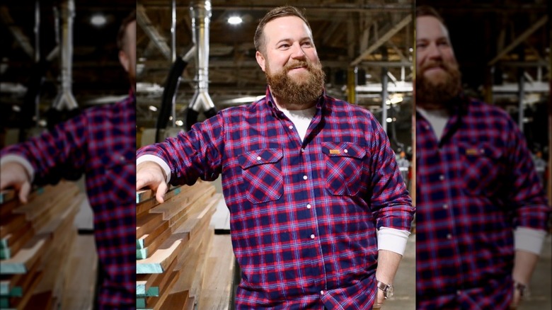 Ben Napier smiles while posing next to wood