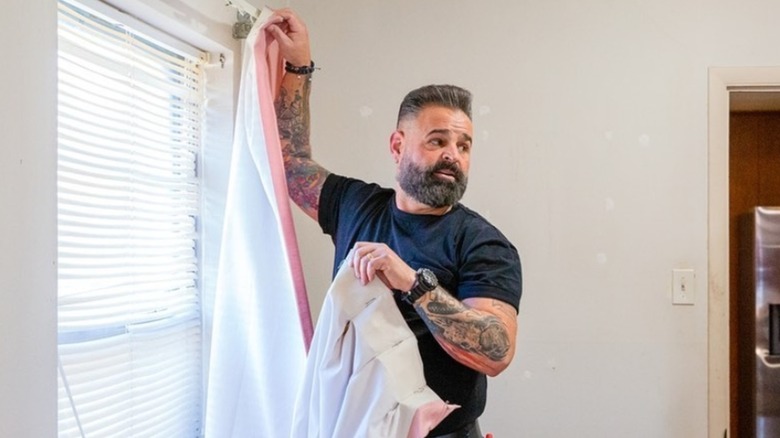 Russell J. Holmes hanging up a curtain and talking