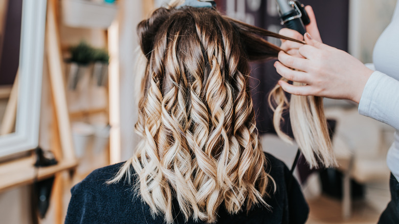 Woman having her highlighted hair styled at the salon