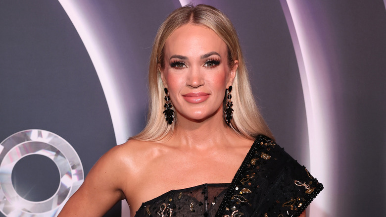 Carrie Underwood posing on the red carpet in a sparkly black dress