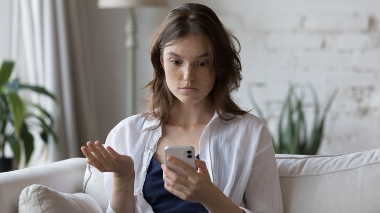 Woman looks at phone shocked