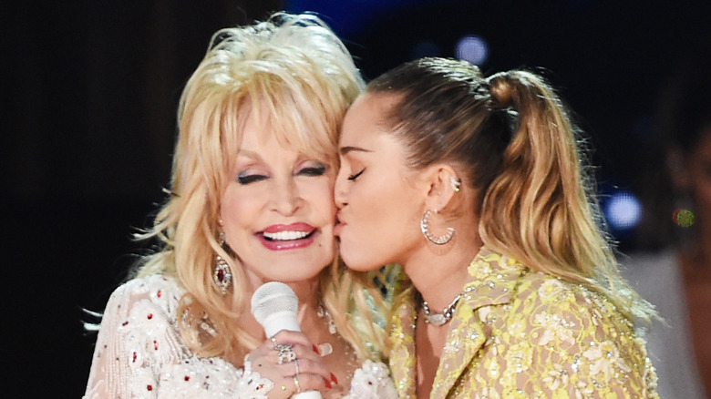 Miley Cyrus kissing Dolly Parton on the cheek