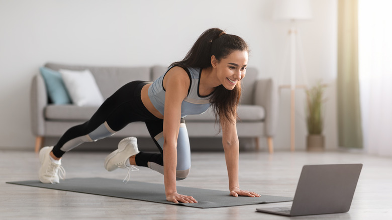 Smiling woman follows online exercise tutorial