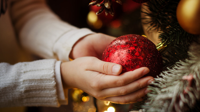 A person holding a Christmas ornament in their hands.