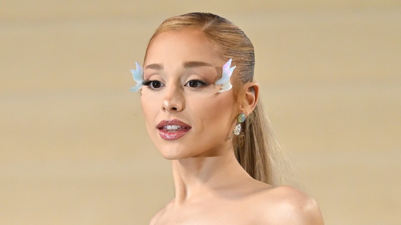 Ariana Grande with crystal wings on sides of her face and crystal earrings.