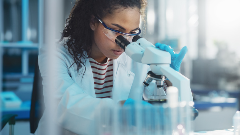 Black woman looking through microscope