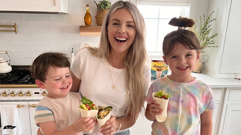 Ali Fedotowsky-Manno and kids smiling in kitchen