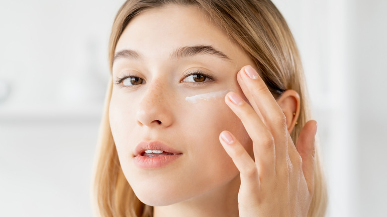 Woman putting eye cream on her face