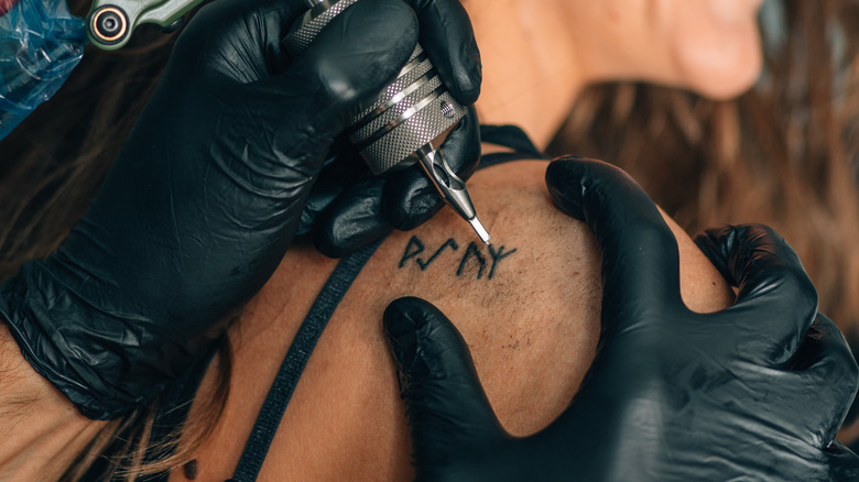 Woman getting tattooed on shoulder