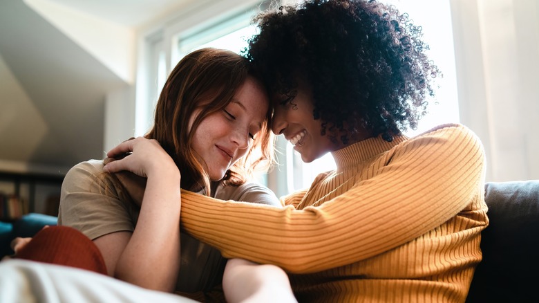 LGBTQIA+ couple hugging on a sofa