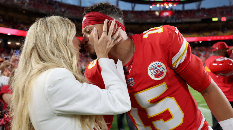 Brittany Mahomes and Patrick Mahomes about to kiss on the field at a game