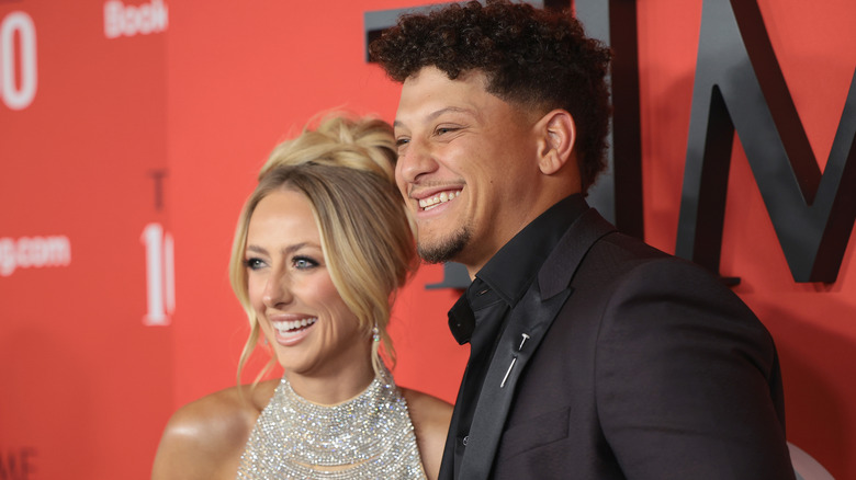 Brittany and Patrick Mahomes smiling while posing together at a red carpet event