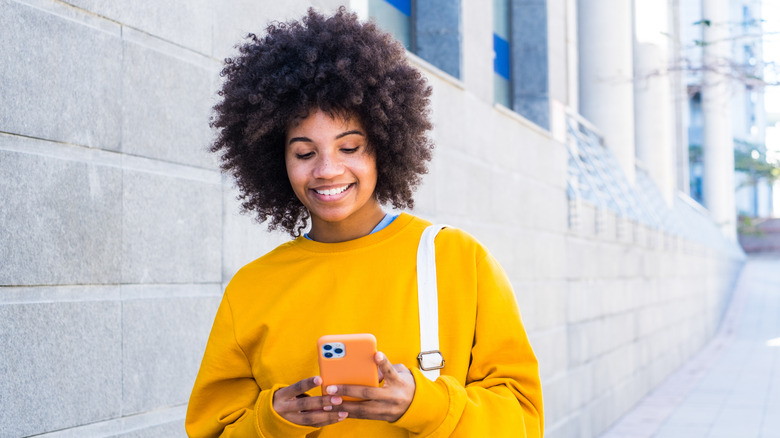 woman scrolling on cell phone while walking