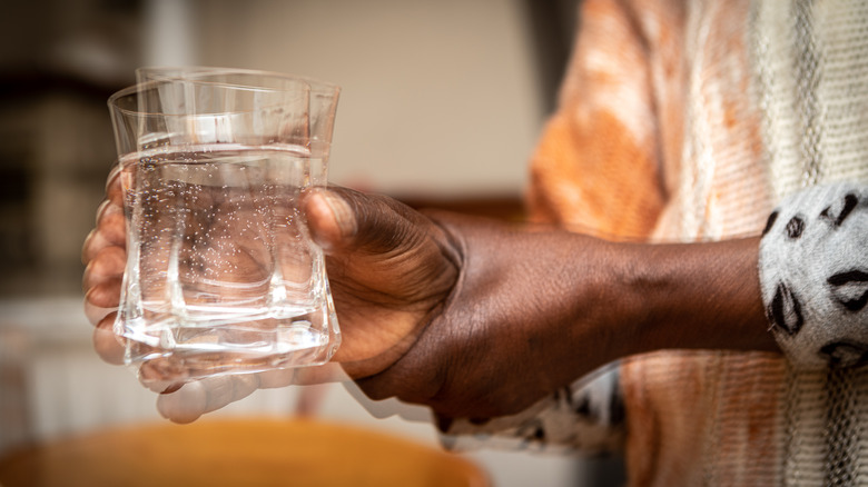 Man with Parkinson's disease struggling to hold a glass of water