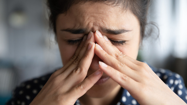 close-up of woman going through anxiety and holding hands to bridge of nose