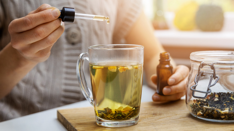 Photo of a woman dropping CBD oil into tea