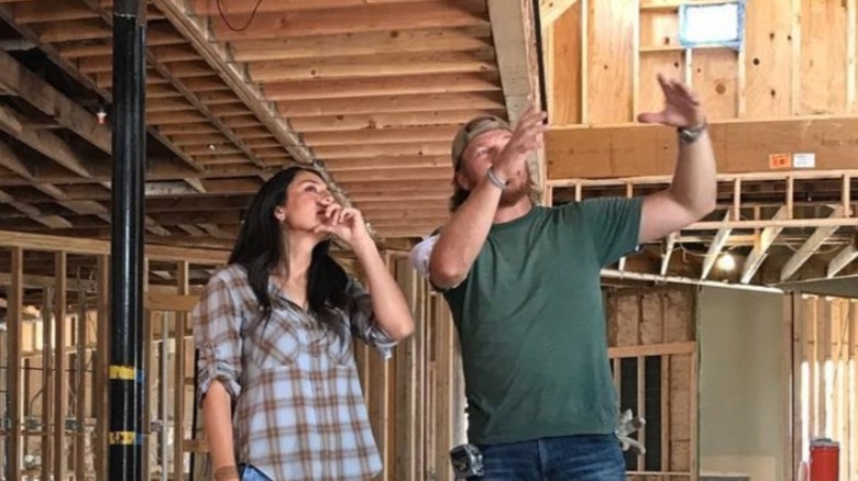 Chip Gaines and Joanna Gaines talking in a partially built house