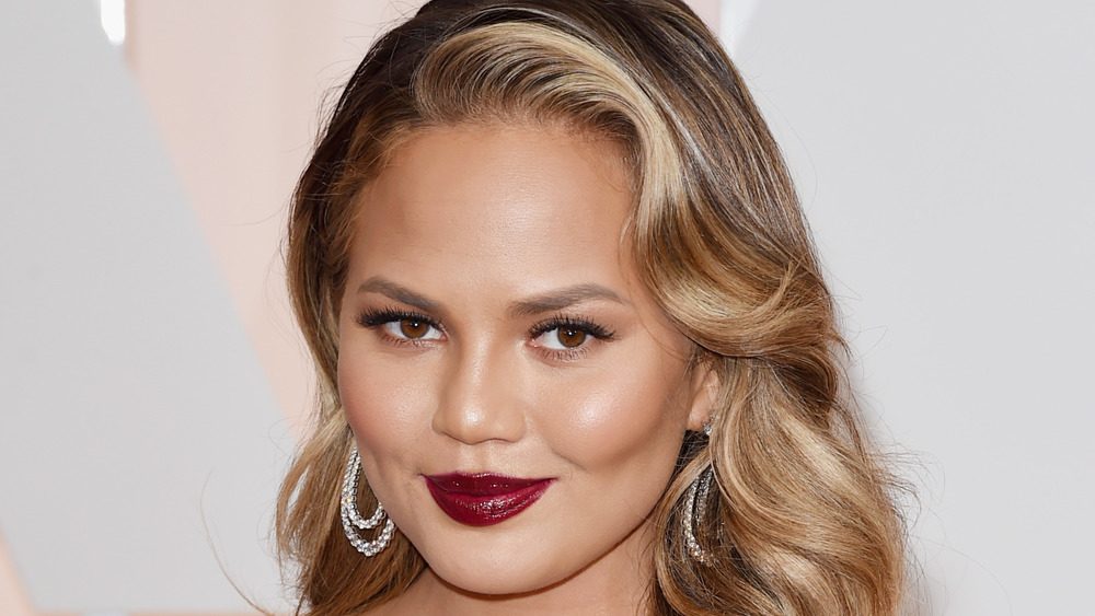 Chrissy Teigen smiling, red lipstick