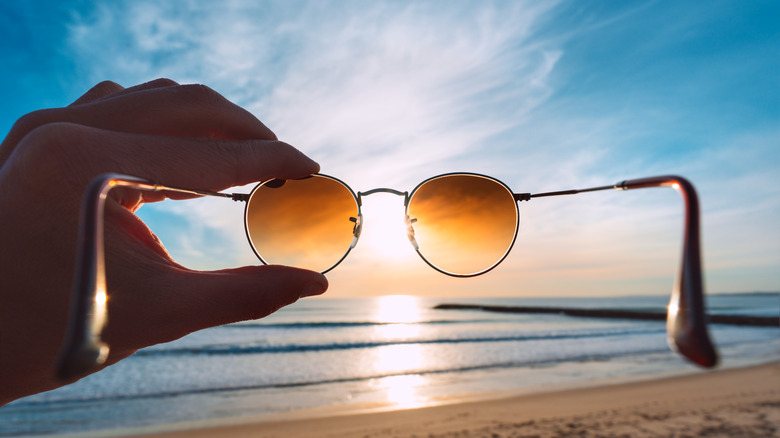 hand holding sunglasses to sun