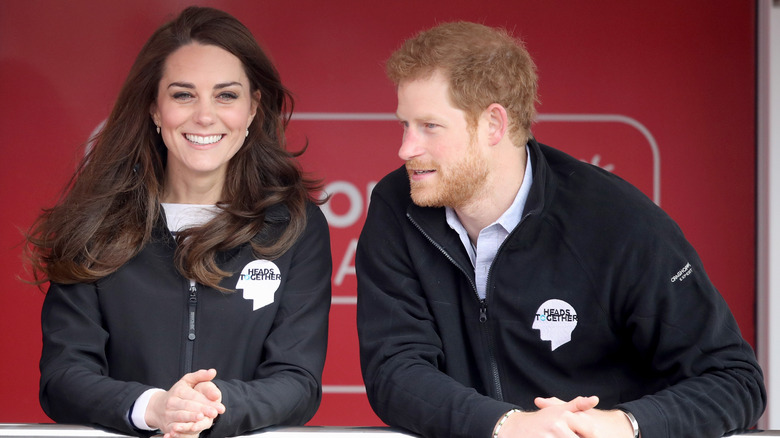 A laughing Princess Catherine and Prince Harry engaging in conversation