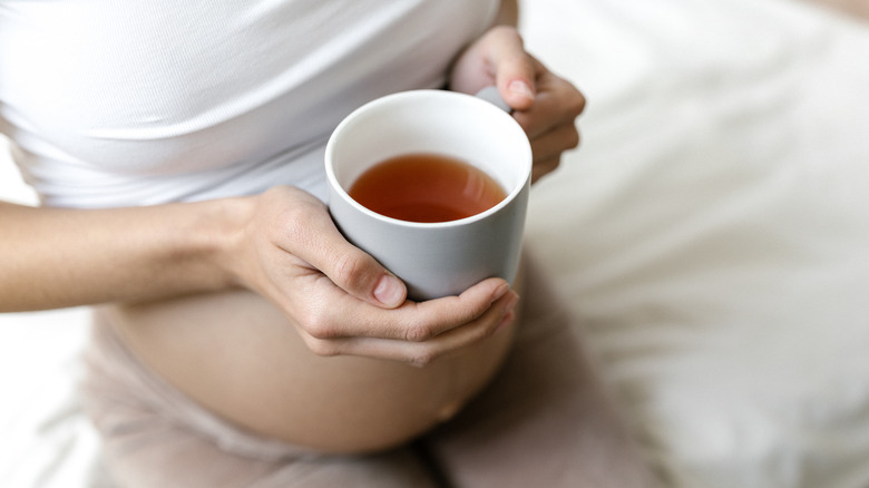 Pregnant woman holding cup of coffee