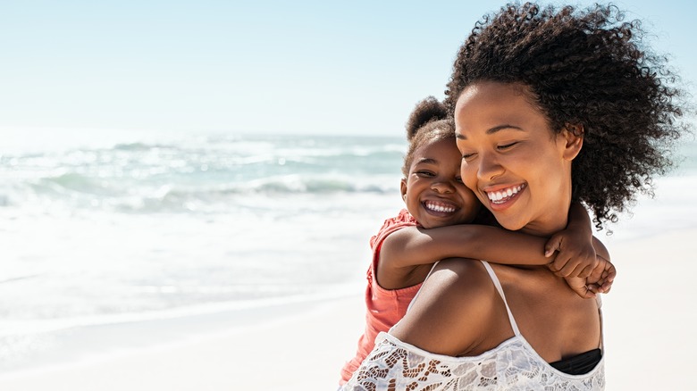 A woman and child smiling at the beach 