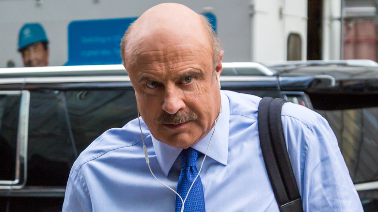 Dr. Phil wearing earbuds and a backpack
