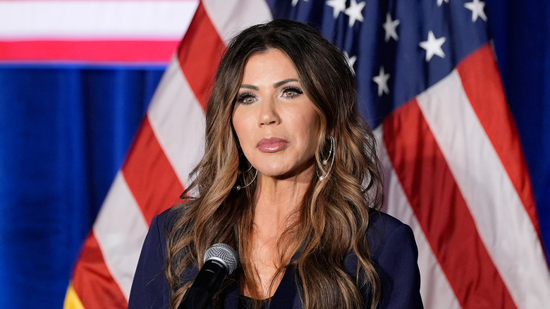 Kristi Noem standing in front of the American flag