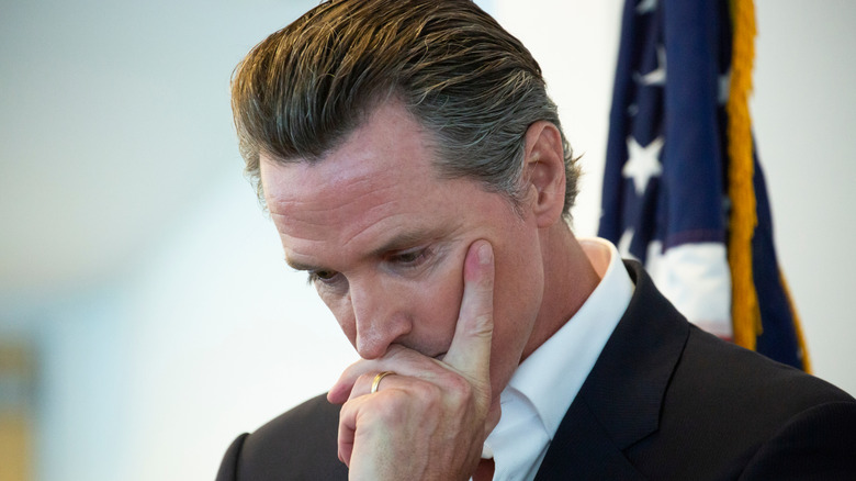 image of California Governor Gavin Nelson looking down and with his index finger pressed on his left cheek