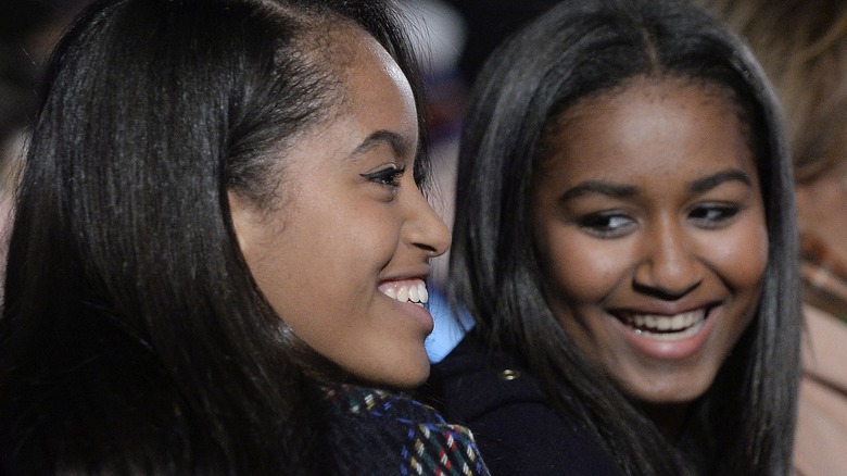 Malia and Sasha Obama smiling at a tree lighting 